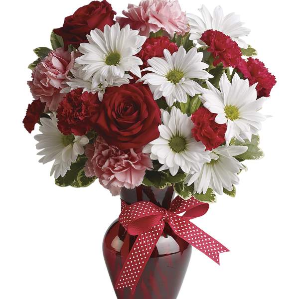 Red and white bouquet in a red vase with a polka-dot ribbon