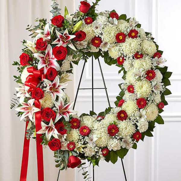 Large red and white standing wreath with roses, lilies, and chrysanthemums on an easel
