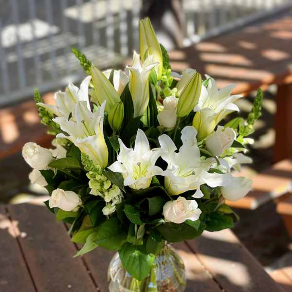 White lilies and pale roses arranged in a clear glass vase