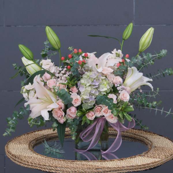 Bouquet of white lilies, pink roses, and hydrangea in a glass vase