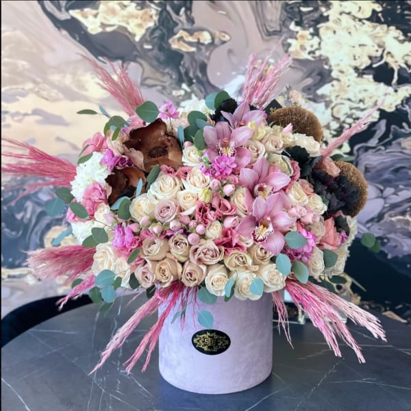 Pink and cream rose arrangement in a lavender hat box with orchids