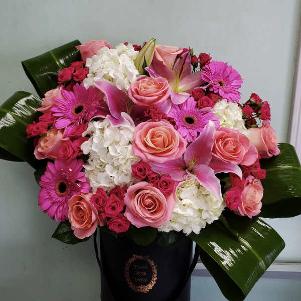 Pink roses, lilies, gerbera daisies, and white hydrangeas in a black hatbox