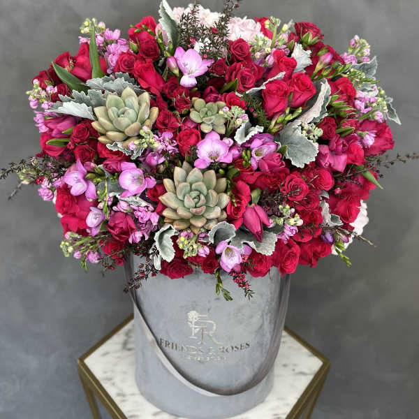 Large bouquet of red and pink roses with succulents in a gray hatbox