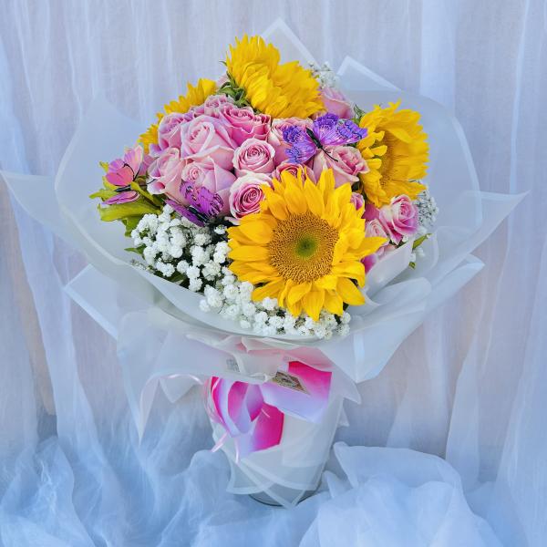 Bouquet of pink roses and yellow sunflowers wrapped in white paper