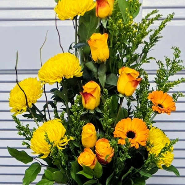 Yellow chrysanthemums and orange roses in a silver vase
