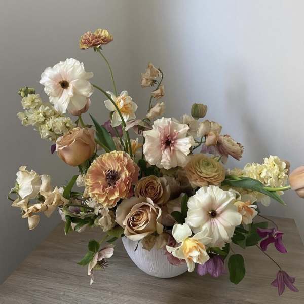 Mixed pastel flower arrangement in a white vase on a table