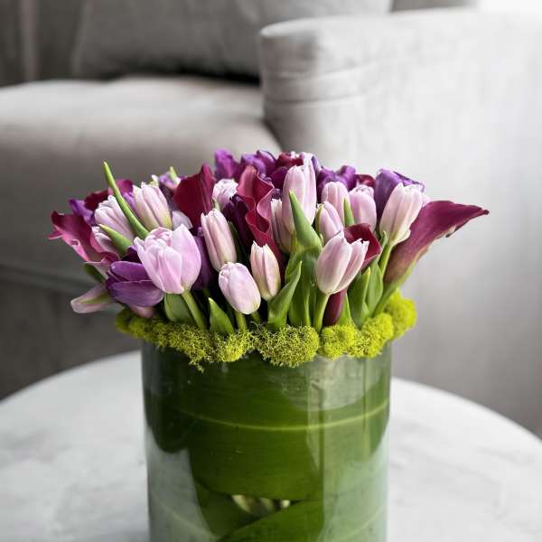Purple and pink tulips arranged in a green glass vase