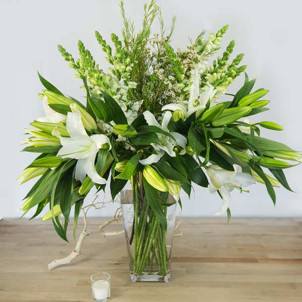 White lilies and green snapdragons in a clear glass vase