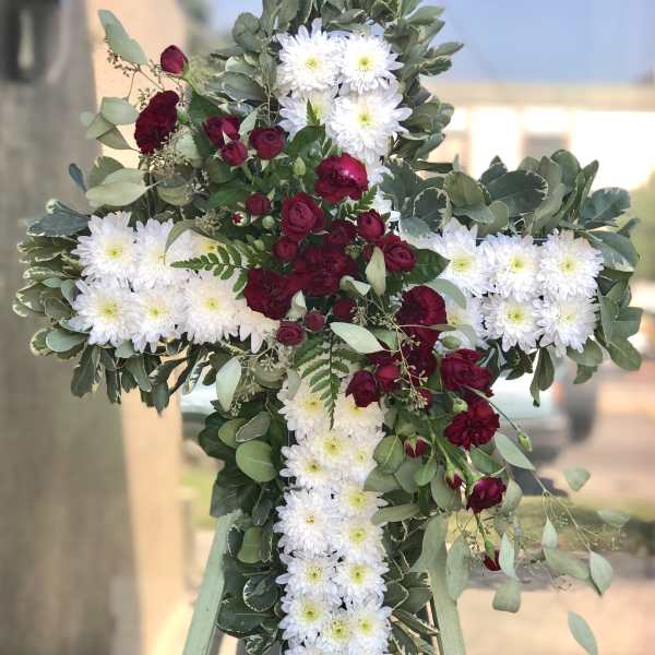 Cross-shaped floral tribute with white daisies and burgundy roses