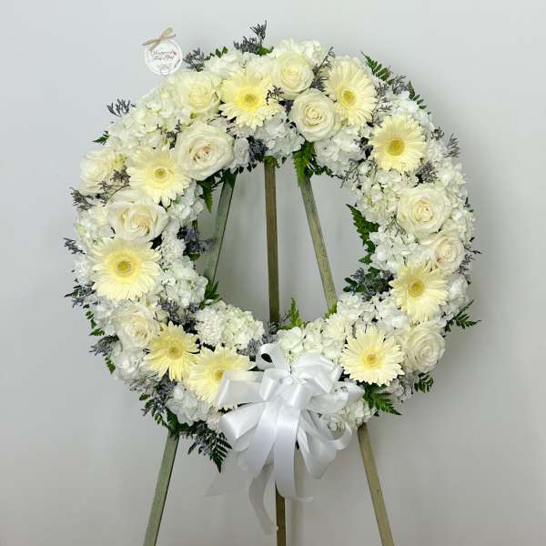 White floral wreath on an easel with a ribbon bow