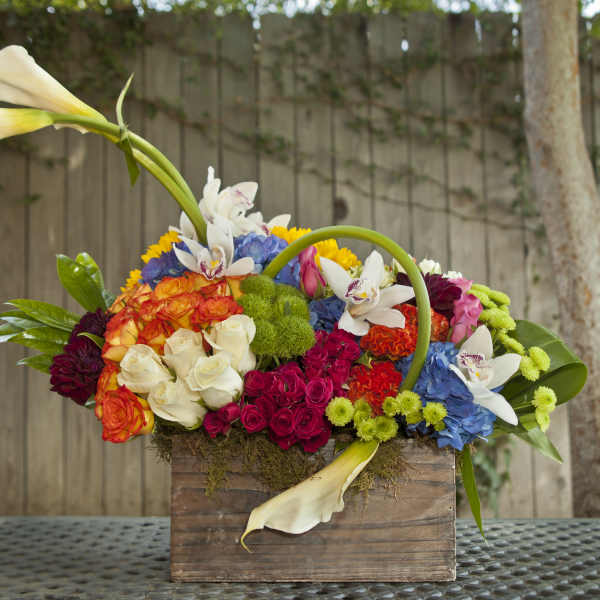 Colorful floral arrangement in a wooden box with white calla lilies