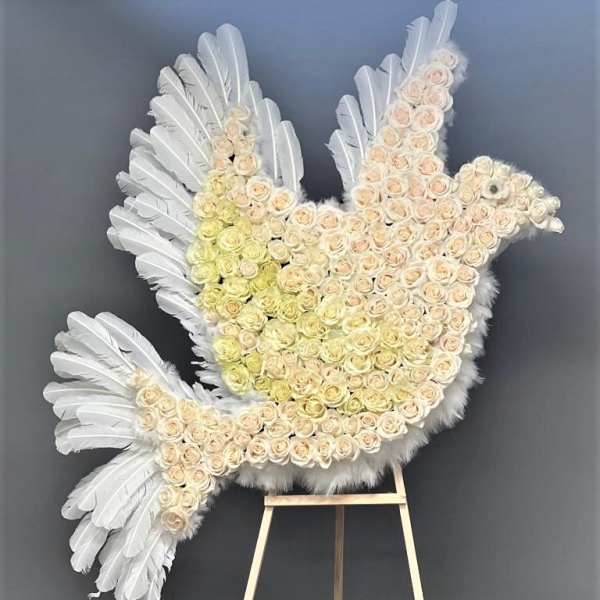White feathered dove-shaped floral tribute on an easel
