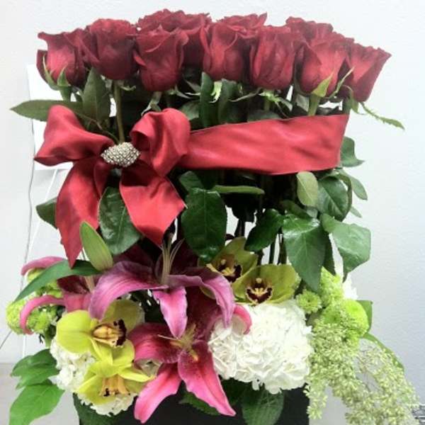 Red roses and pink lilies in a black box with a red ribbon