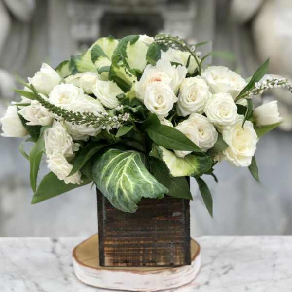 White rose bouquet in a rustic wooden box with green foliage