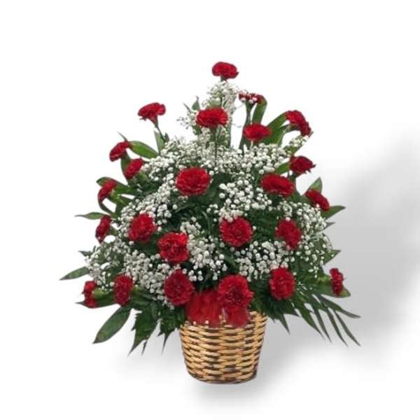 Red carnations in a woven basket with white filler flowers