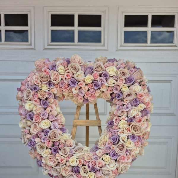 Heart-shaped rose arrangement on an easel in pastel pink, lavender, and cream