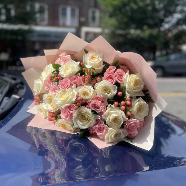 Bouquet of pink and white roses wrapped in pale pink paper