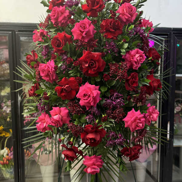 Large standing spray of red and pink roses with purple accents
