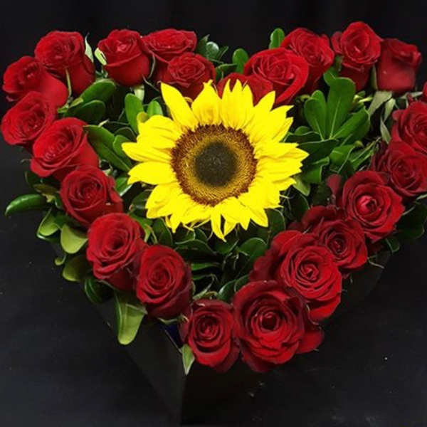 Heart-shaped bouquet of red roses with a yellow sunflower center