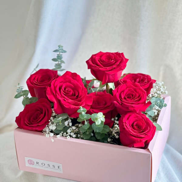 Pink box arrangement of red roses with white filler flowers