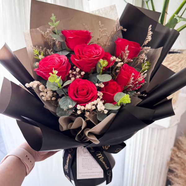 Bouquet of red roses wrapped in black paper