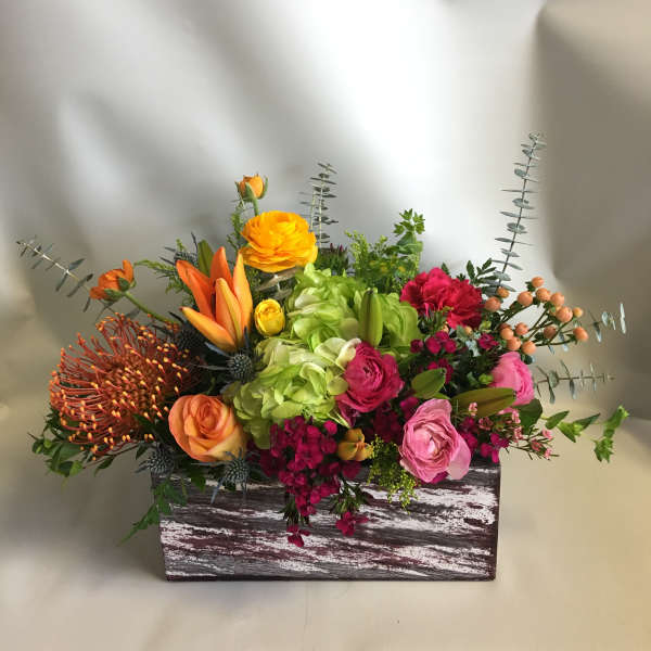 Colorful mixed flower arrangement in a rustic wooden box
