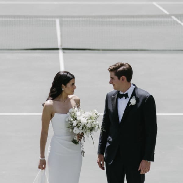Bride holding a white bouquet beside a groom in a tuxedo