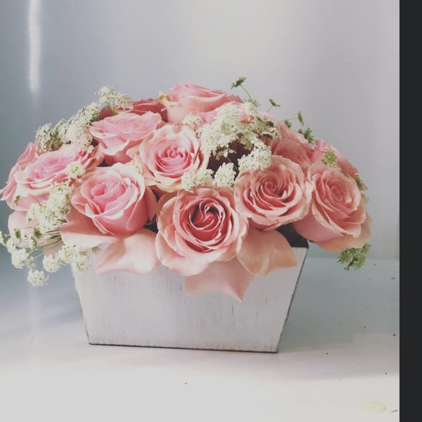 Pink roses arranged in a white wooden box with white filler flowers