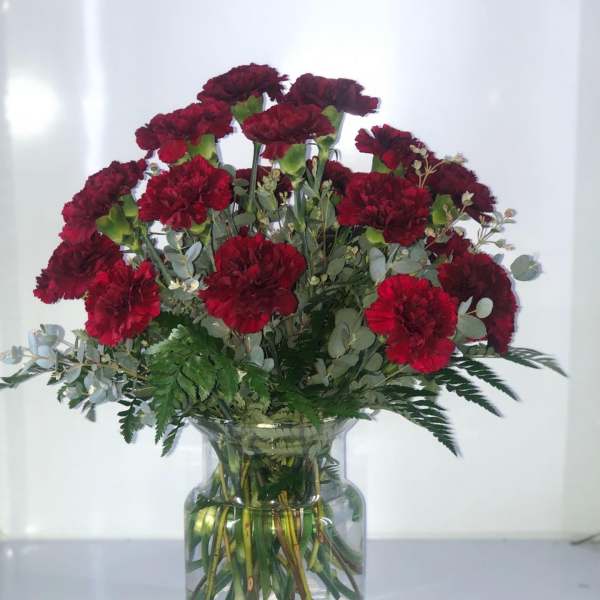 Red carnations arranged in a clear glass vase