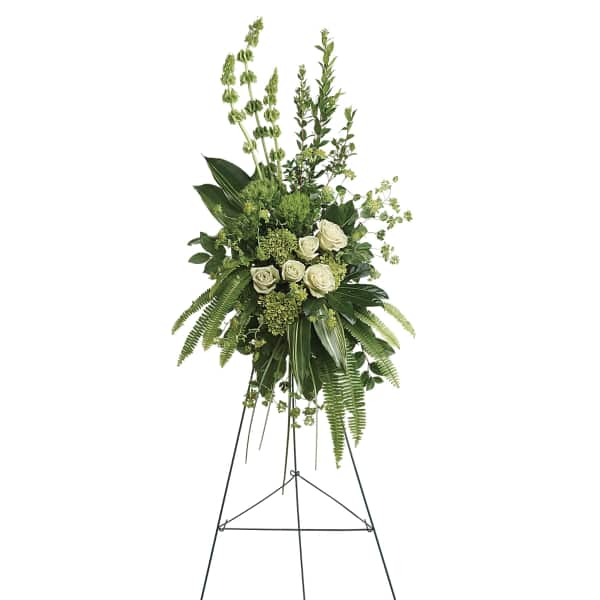 Tall white rose standing spray on a metal easel with lush greenery