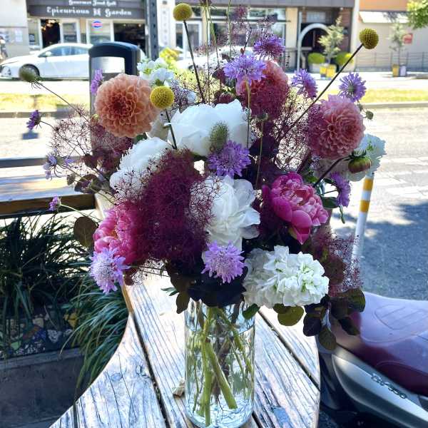 Mixed bouquet of pink, white, and purple flowers in a clear glass vase