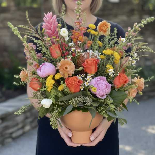Mixed bouquet in a terracotta vase with pink, orange, yellow, and white blooms