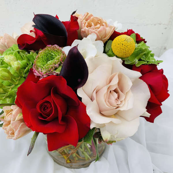 Bouquet of red, white, and peach flowers in a glass vase