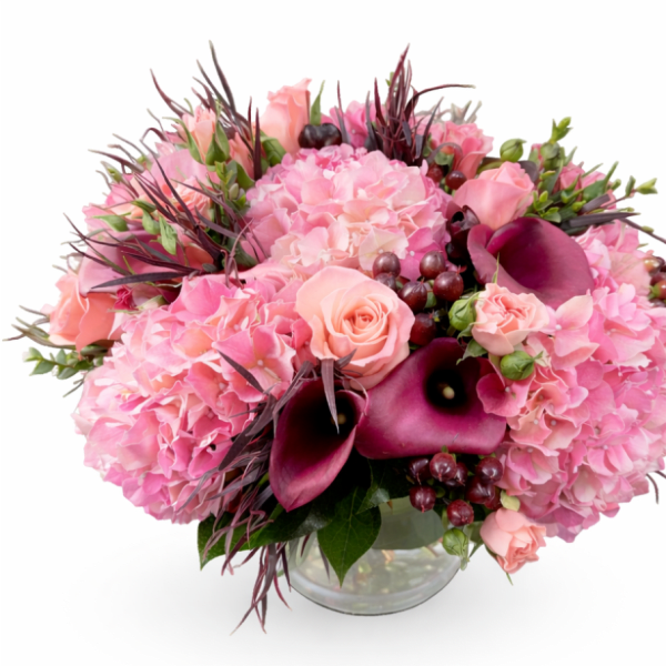 Pink floral arrangement with roses, hydrangeas, and dark calla lilies in a glass vase