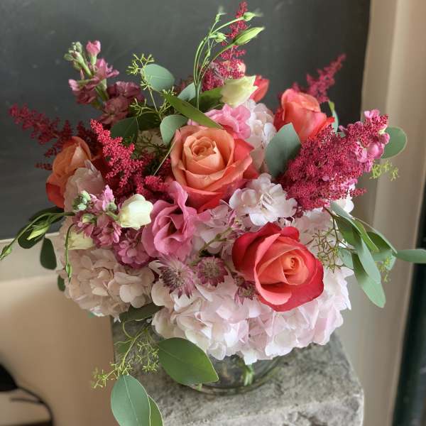 Bouquet of coral and pink roses with pale hydrangeas in a glass vase