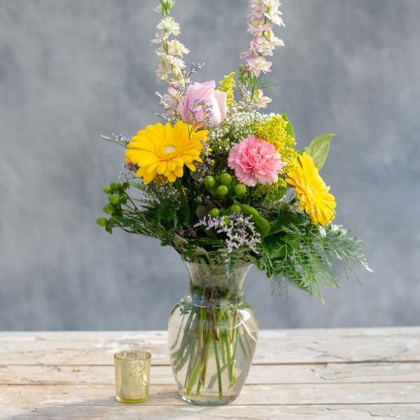 Mixed bouquet in a glass vase with yellow daisies and pink flowers