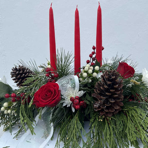 Holiday centerpiece with red candles, roses, pinecones, and evergreen branches