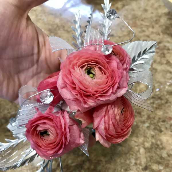 Small pink ranunculus bouquet with silver ribbon and decorative accents