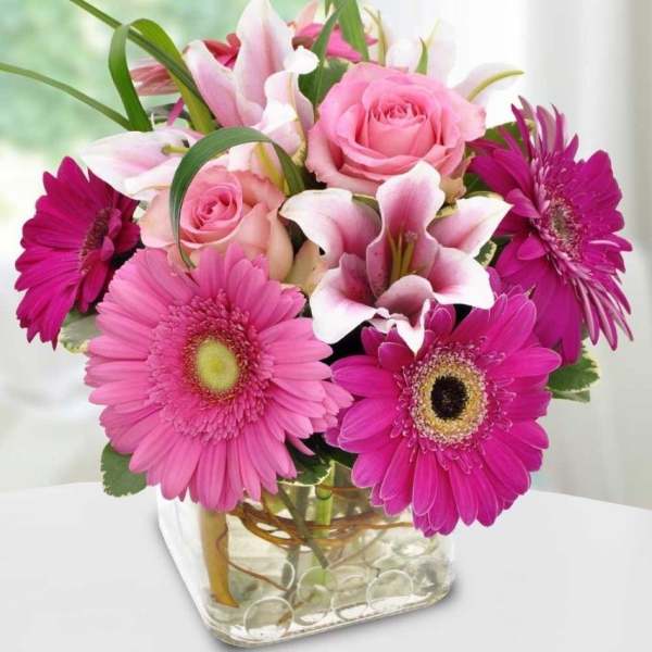 Pink roses and lilies with magenta gerbera daisies in a glass vase