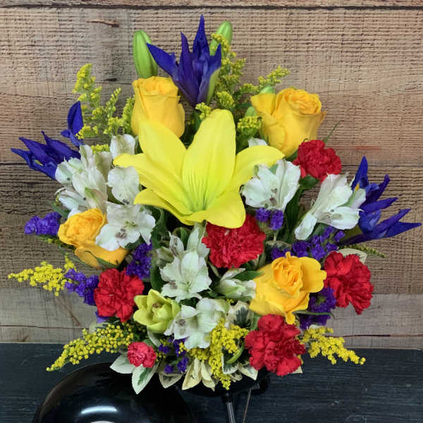 Bright mixed bouquet with yellow lilies, roses, and white alstroemeria in a black vase
