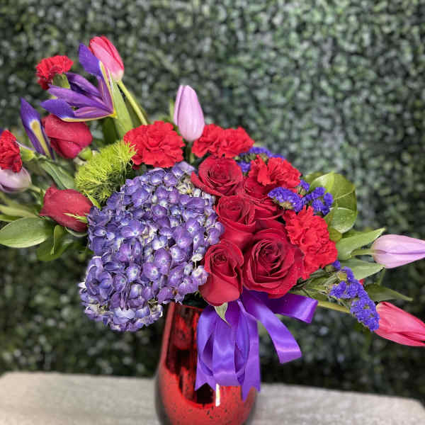 Bouquet of red roses, purple hydrangea, and tulips in a red vase
