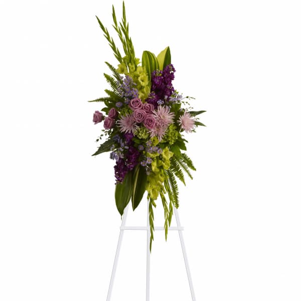 Tall floral standing spray with purple and green flowers on a white easel