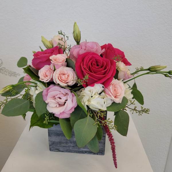 Pink and white rose arrangement in a square gray vase