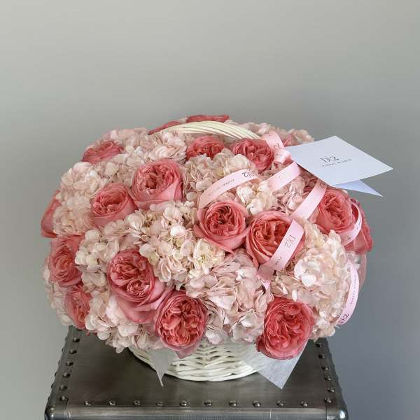 Pink roses and pale hydrangeas arranged in a white basket