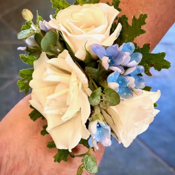 Small wrist corsage with white roses and blue flowers