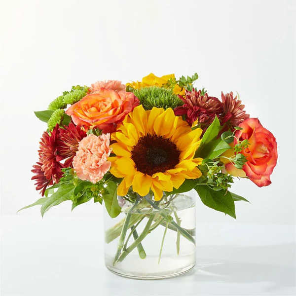 Mixed bouquet with a sunflower, roses, and chrysanthemums in a glass vase