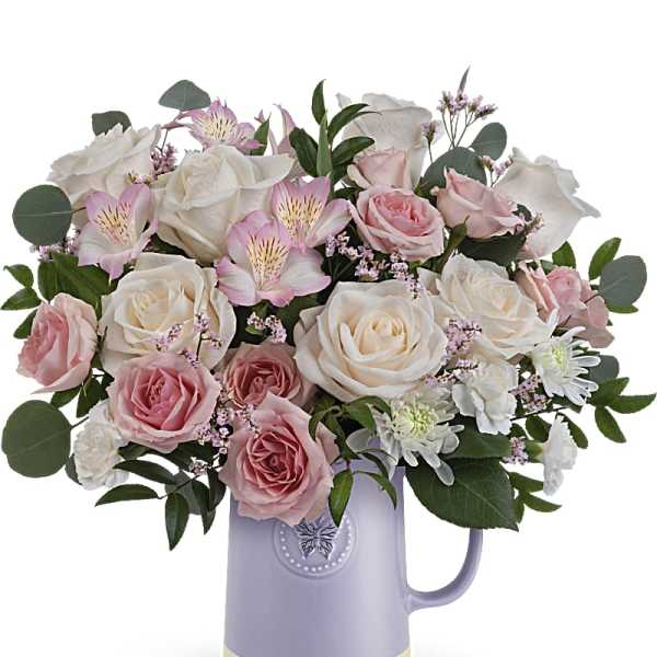 Pink and white roses arranged in a lavender pitcher vase