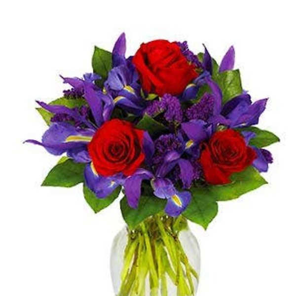 Bouquet of red roses and purple flowers in a clear glass vase