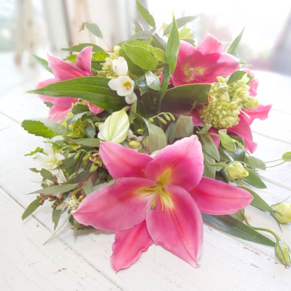Pink lilies and white flowers arranged low on a table