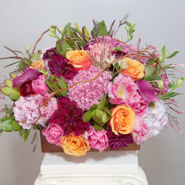 Pink and orange floral arrangement in a rectangular container